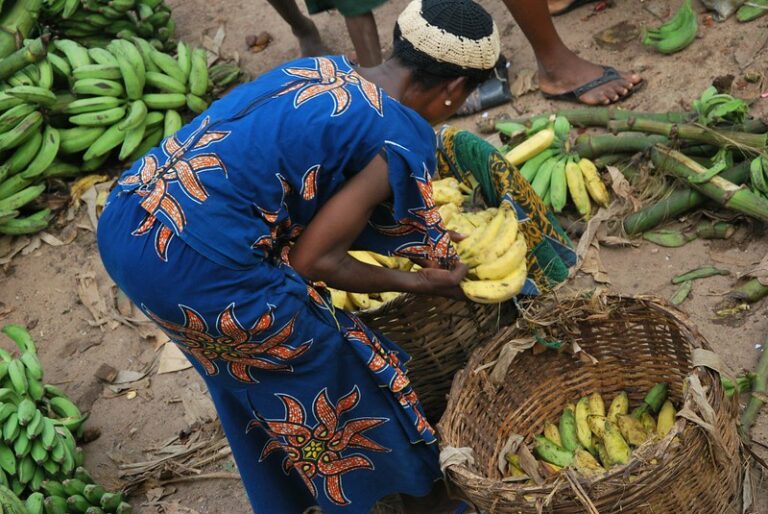 A woman picks bananas in a marketplace.