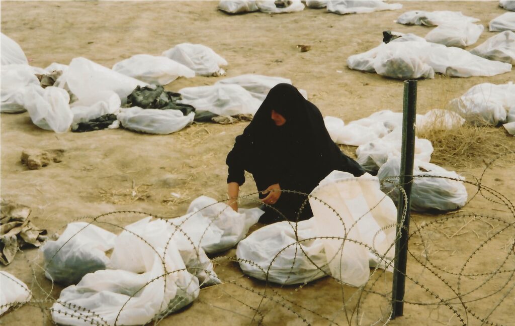 A woman near a mass grave searching for evidence of a loved one.